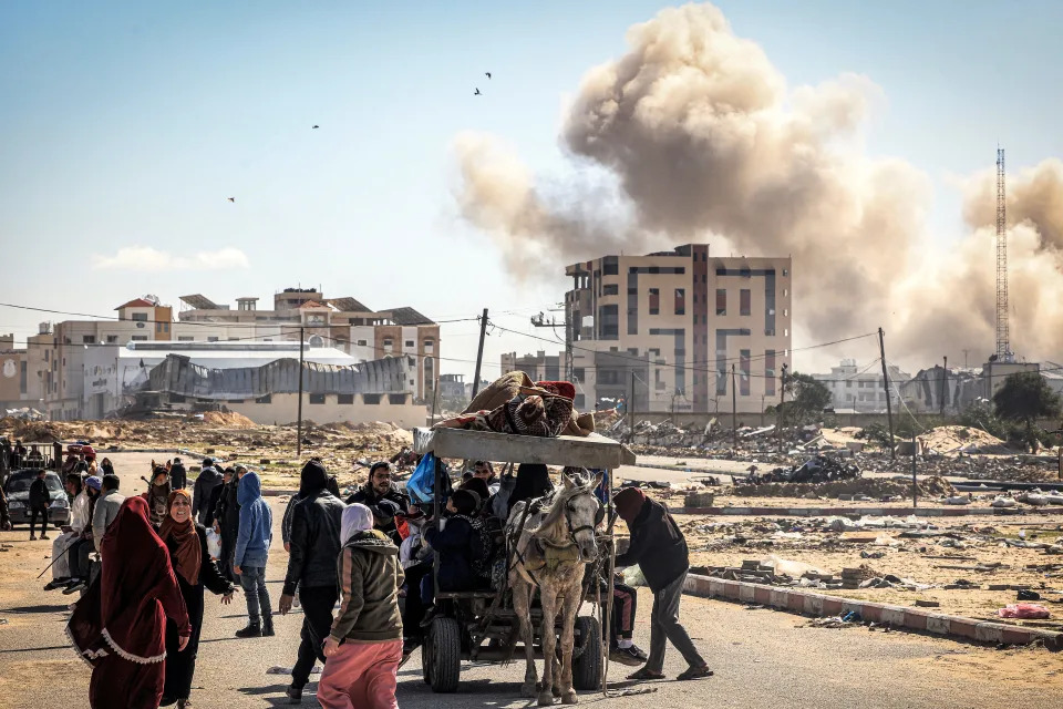 January 30, 2024: Smoke from bombardment billows in the background as displaced Palestinians flee from Khan Yunis in the southern Gaza Strip, amid the ongoing conflict between Israel and the Palestinian militant group Hamas.