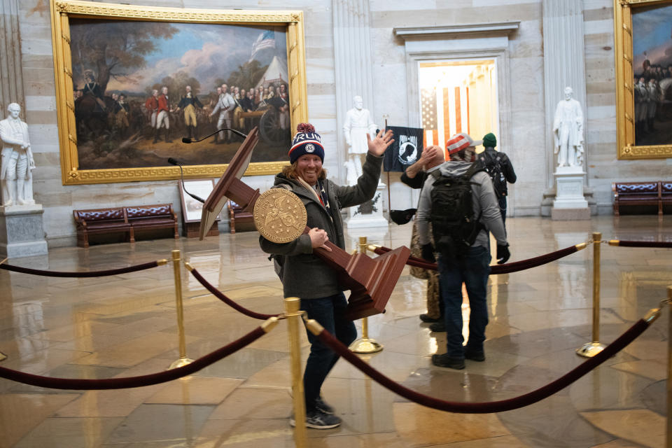 A pro-Trump protester carries the lectern of U.S. Speaker of the House Nancy Pelosi through the Roturnda of the U.S. Capitol Building after a pro-Trump mob stormed the building on January 06, 2021 in Washington, DC. (Win McNamee/Getty Images)