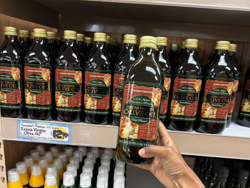 hand holding a bottle of olive oil at trader joes