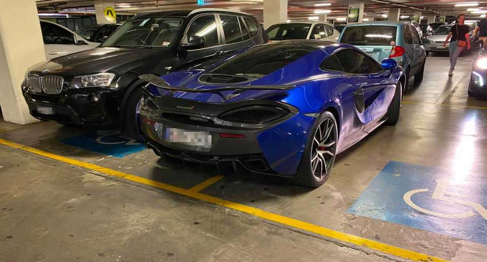 McLaren car parked across two disabled parking spots.