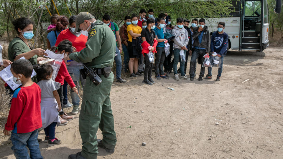 A U.S. Border Patrol agents questions families, as a group of unaccompanied minors (R), looks on after they crossed the Rio Grande into Texas on March 25, 2021 in Hidalgo, Texas. (John Moore/Getty Images)