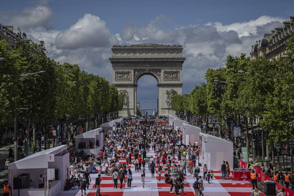 People eat their lunches as part of a giant picnic on the Champs-Elysées, in front of the Arc de Triomphe, organized by the Comité Champs-Élysées, Sunday, May 26, 2024 in Paris. (AP Photo/Aurelien Morissard)