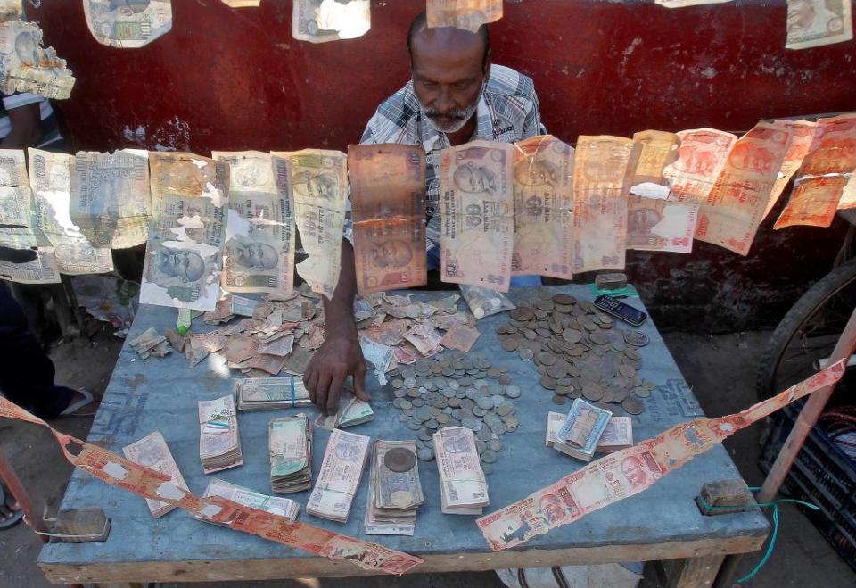 A roadside currency exchange vendor sorts Indian currency notes at his stall in Agartala