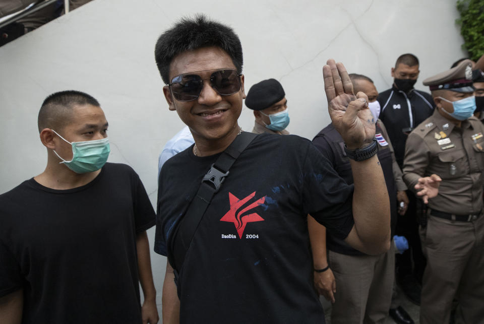 Activist Jatupat Boonpattararaksa, second left, raises a three-finger salute, a symbol of resistance, as he turns up at Samranrat police station in Bangkok, Thailand, Friday, Aug, 28, 2020. Anti-government protesters tussled with police on Friday as 15 of their movement leaders turned up at a police station to answer a summons linked to demonstrations denouncing the arrests. (AP Photo/Sakchai Lalit)