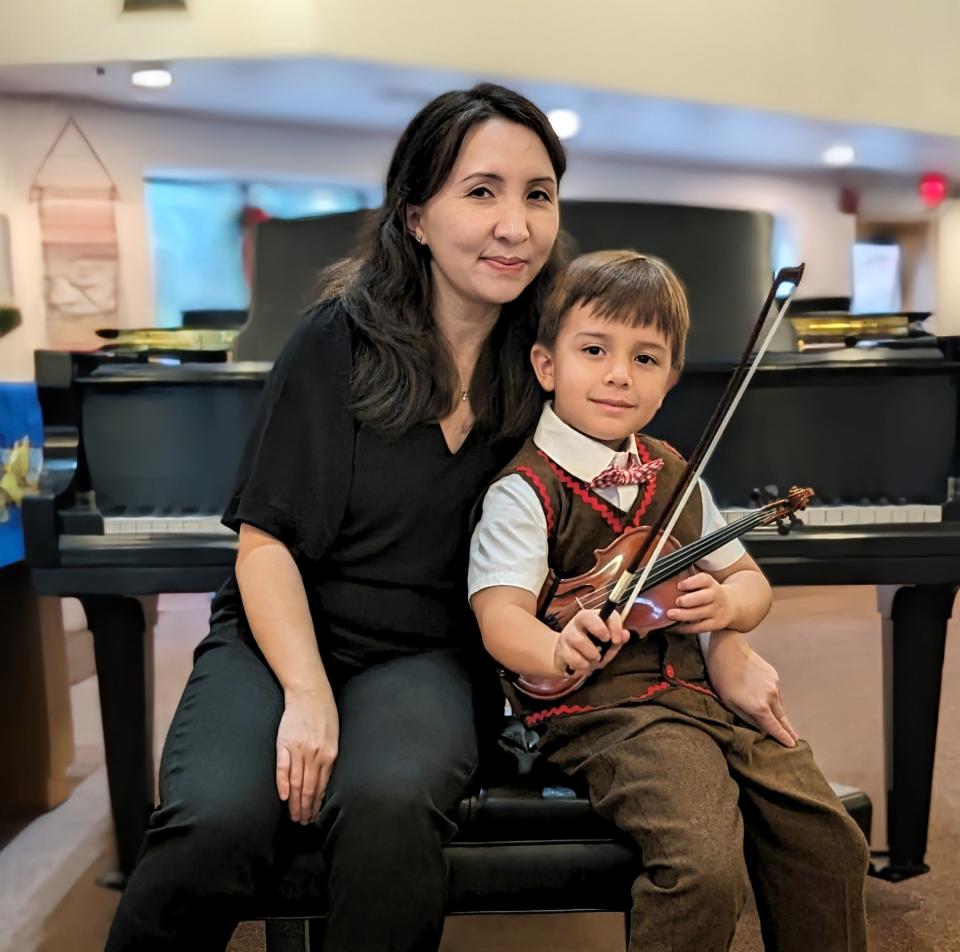 FSU assistant professor of composition Liliya Ugay poses at the piano with her son.