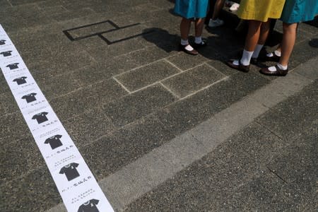 FILE PHOTO: Students stand next to signs pasted on the floor calling on people to wear black as a sign of mourning on October 1, during a rally as part of a strike on the eve of China's National Day, at Chater Garden in Hong Kong