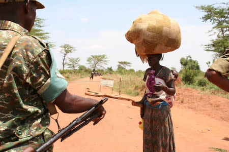 A South Sudanese refugee woman carries her child and belongings as she talks to a Uganda People's Defence Forces (UPDF) soldier after crossing into Uganda at the Ngomoromo border post in Lamwo district, northern Uganda, April 4, 2017. REUTERS/Stringer