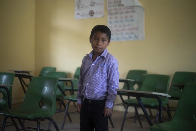 Hector Vasquez poses for a portrait inside his former classroom at the Nuevo Yibeljoj school, closed amid the new coronavirus pandemic in Chiapas state, Mexico, Friday, Sept. 11, 2020. Since schools closed in March, Vasquez is one of 12 siblings who work in the coffee fields daily instead of just the weekends, while his father helps them with school work dropped off by teachers. (AP Photo/Eduardo Verdugo)
