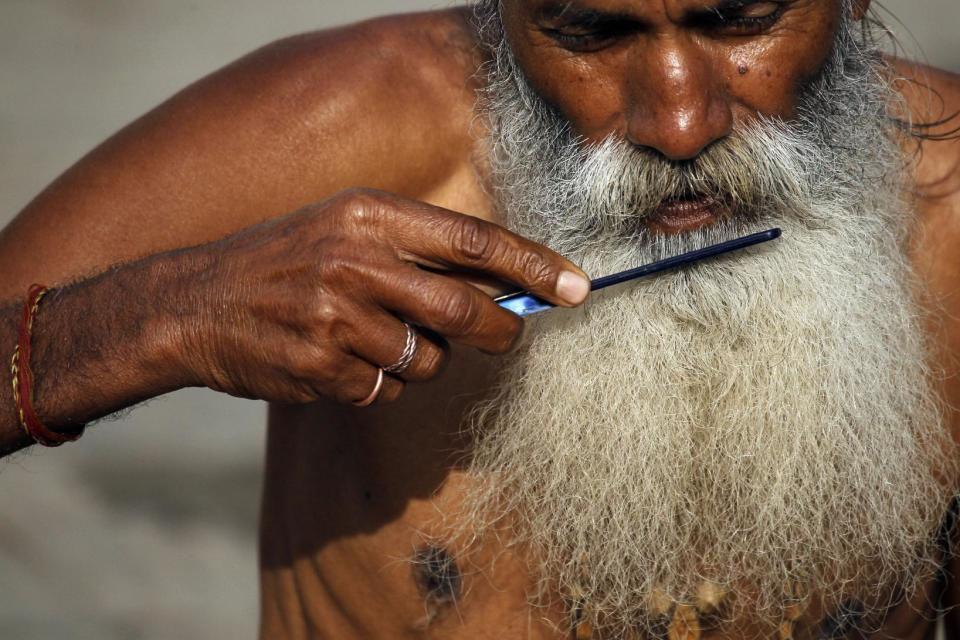 In this Tuesday, Feb. 21, 2017 photo, a Hindu holy man combs his beard in the courtyard of Pashupatinath temple in Kathmandu, Nepal. Hindu holy men from Nepal and India have started arriving at the temple ahead of the Shivratri festival, dedicated to the worship of Lord Shiva which falls on Feb. 23. (AP Photo/Niranjan Shrestha, File)