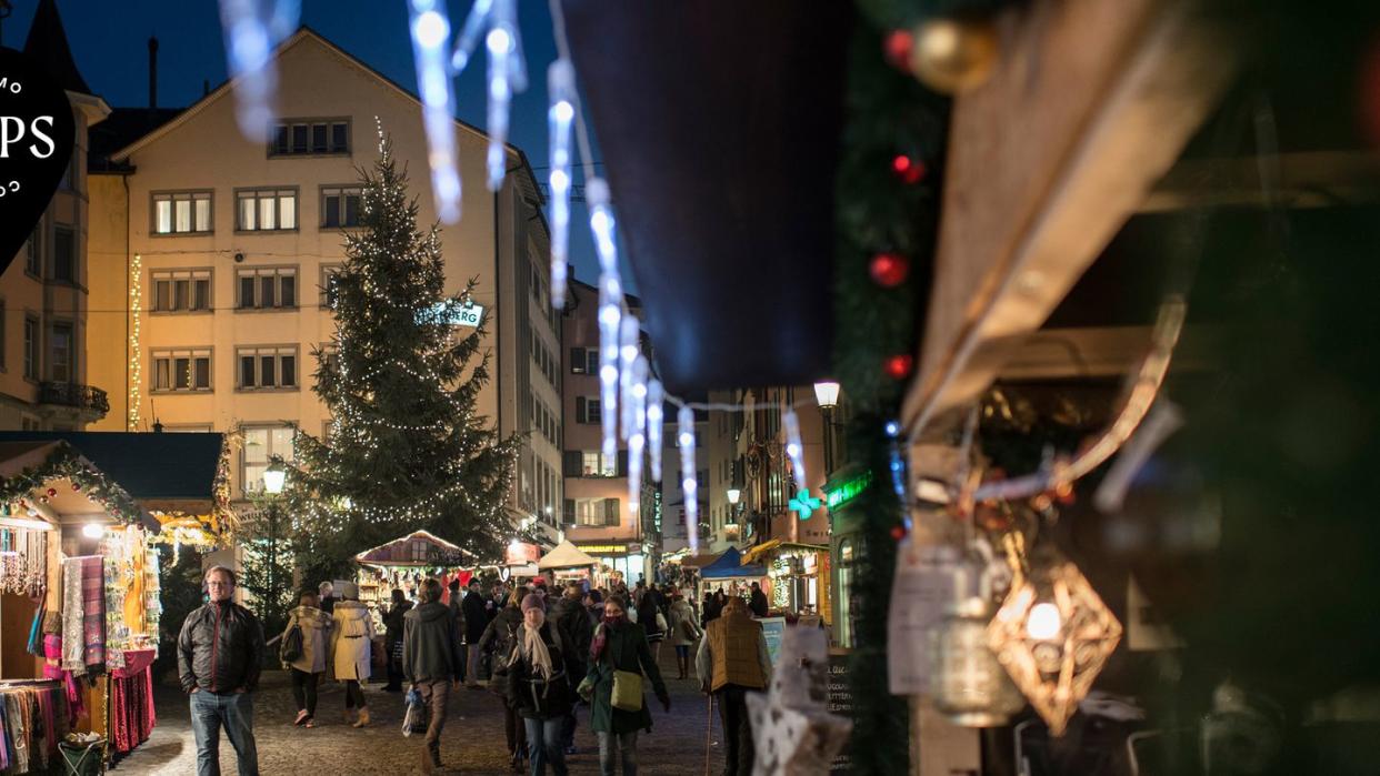 a group of people walking around a christmas tree in a city