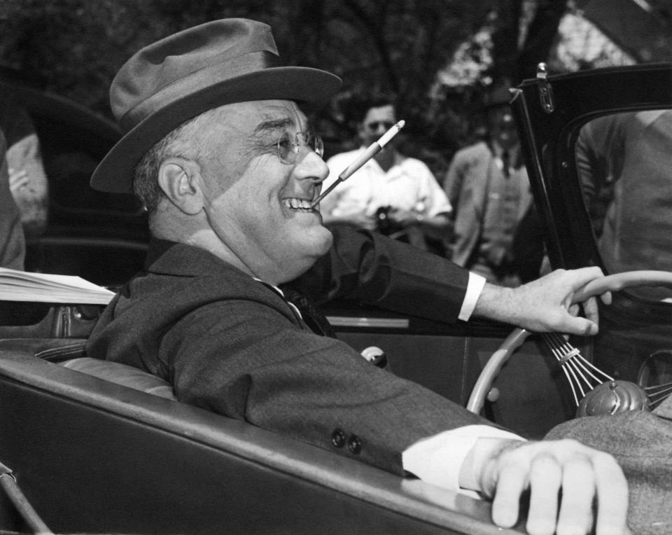 With a cigarette in a holder clenched in his teeth, Franklin D. Roosevelt sits jauntily at the wheel of his convertible in Warm Springs, Ga., in 1939. (Photo: Underwood Archives/Getty Images)