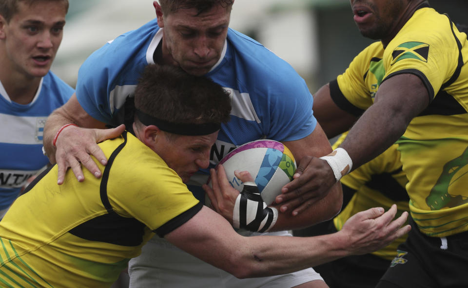 Matias Osadczuk of Argentina, center, is tackled by Rhodri Adamson of Jamaica, left, during rugby seven match at the Pan Am Games in Lima, Peru, Friday, July 26, 2019. Argentina won the match 52-0. (AP Photo/Juan Karita)