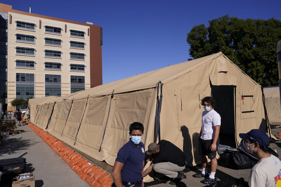 Engineers and volunteers stand outside a mobile field hospital at UCI Medical Center, Monday, Dec. 21, 2020, in Orange, Calif. California's overwhelmed hospitals are setting up makeshift extra beds for coronavirus patients, and a handful of facilities in hard-hit Los Angeles County are drawing up emergency plans in case they have to limit how many people receive life-saving care. (AP Photo/Jae C. Hong)