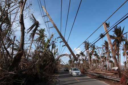 FILE PHOTO: Cars drive under a partially collapsed utility pole, after the island was hit by Hurricane Maria in September, in Naguabo, Puerto Rico October 20, 2017. REUTERS/Alvin Baez/File Photo