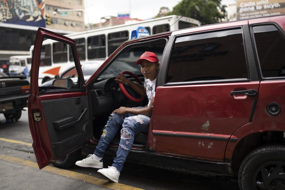 César Sandoval, a taxi driver, poses for a portrait in his car in Caracas, Venezuela, Monday, Feb. 27, 2023. Sandoval first offered motorcycle rides and saved enough money to sell that vehicle and buy a used car. He now owns two cabs. “They are my engine,” Sandoval said of his wife and three children. “(Family) is what motivates me the most every day to go out into the street to look for money... to work.” None of his seven siblings have migrated. (AP Photo/Ariana Cubillos)