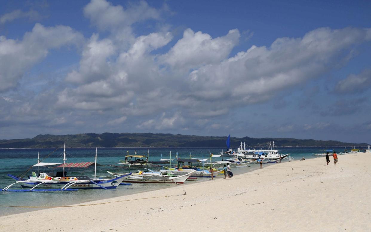 Traditional boats line up the shore in a secluded beach on the island of Boracay, central Philippines - REUTERS