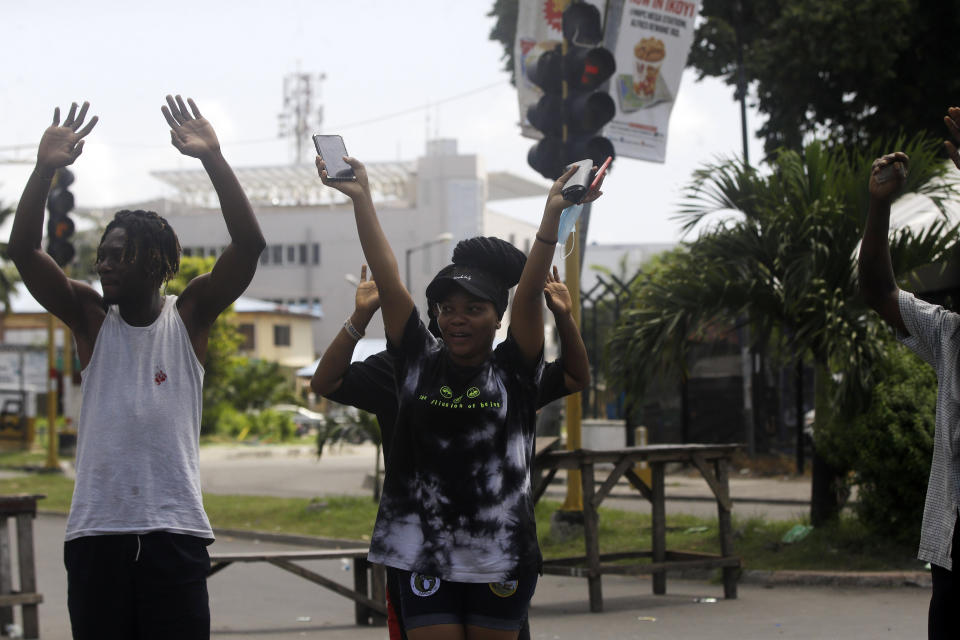 People rise their hands as they approach a police check point in Lagos, Nigeria, Thursday Oct. 22, 2020. Lagos streets were empty and shops were shuttered Thursday, as residents of Nigeria's largest city obeyed the government's curfew, stopping the protests against police brutality that had lasted for two weeks. ( AP Photo/Sunday Alamba)