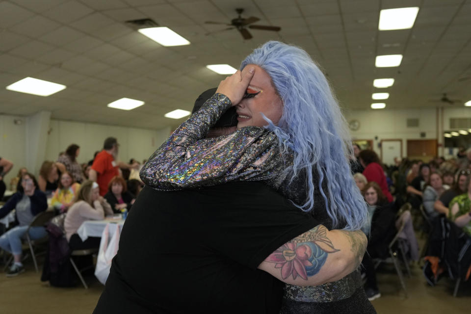 La drag queen Trixy Valentine, alias Jacob Kelley, llora en los brazos del DJ Corrine tras un número musical de su historia drag en el evento de recaudación de fondos "Drag Bingo" en el salón social de la compañía de bomberos voluntarios del municipio de Nescopeck, en Nescopeck, Pensilvania, el sábado 18 de marzo de 2023, para recaudar dinero para un nuevo techo para el Teatro y Centro Comunitario Artístico de Berwick, en Berwick. La emotiva actución de Trixy recibió una ovación. (Foto AP/Carolyn Kaster)