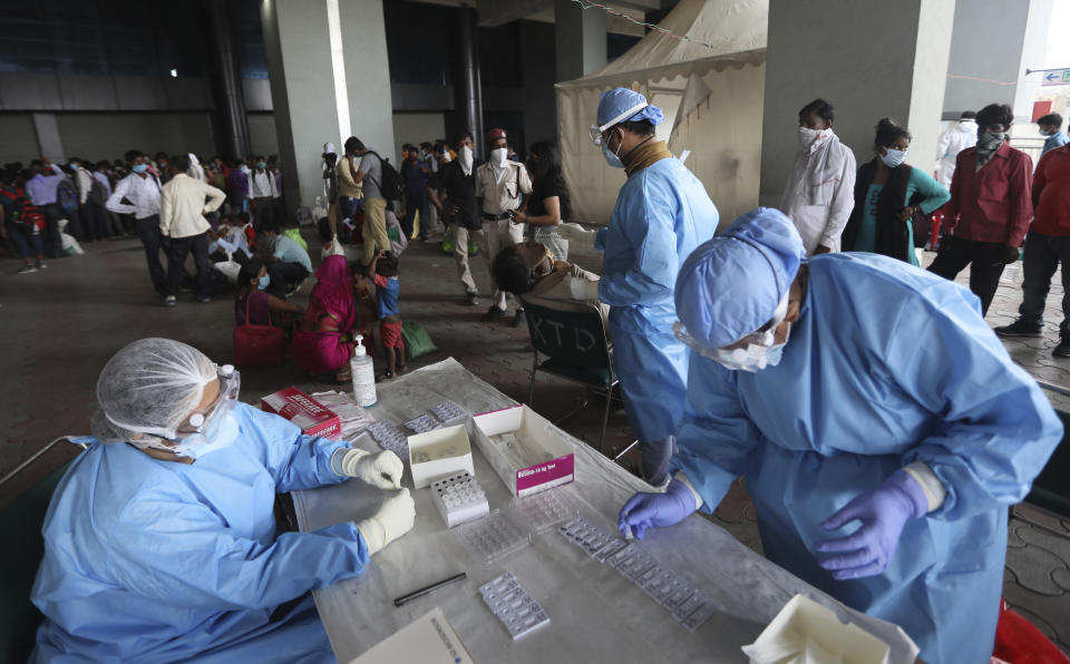 Health workers conduct COVID-19 antigen tests for migrant workers in New Delhi, India, Aug. 18, 2020. In June, India began using the cheaper, faster but less accurate tests to scale up testing for the coronavirus — a strategy that the U.S. is now considering. (AP Photo/Manish Swarup)