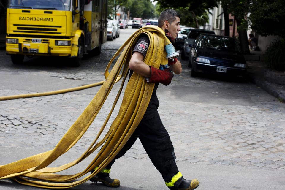 Un bombero lleva mangueras para combatir un incendio en la empresa Iron Mountain en que se habían registrado nueve muertos, incluso bomberos, en Buenos Aires, Argentina, el miércoles 5 de febrero de 2014. (AP Photo/Rodrigo Abd)