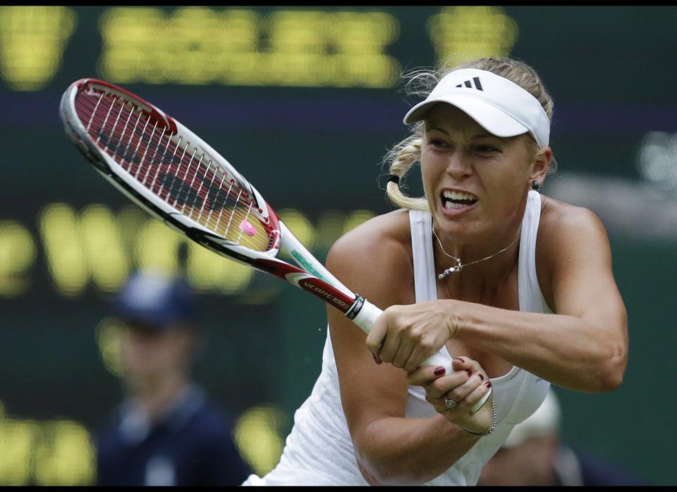 Caroline Wozniacki of Denmark returns a shot to Tamira Paszek of Austria during a first round women's singles match at the All England Lawn Tennis Championships at Wimbledon, England, Tuesday, June 26, 2012. 