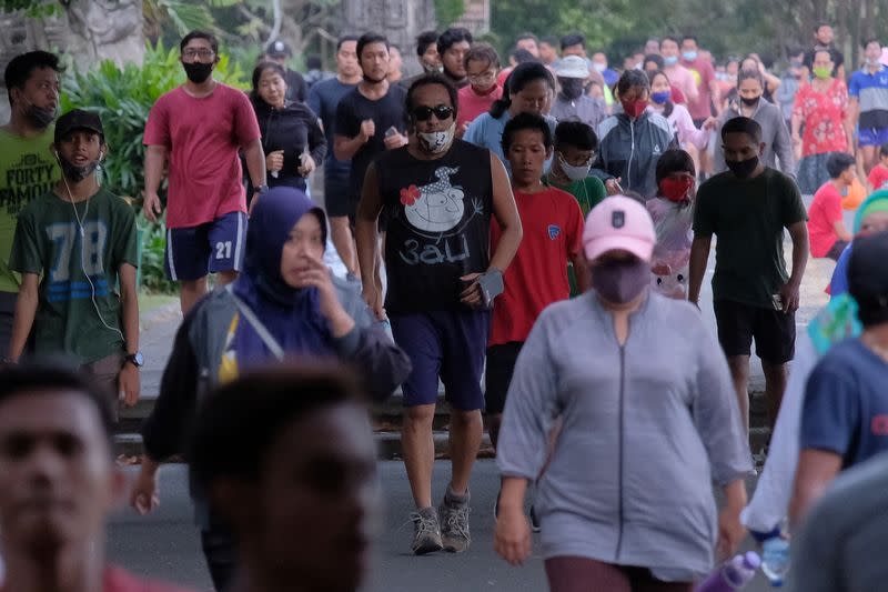 People wearing protective masks walk at the Puputan Margarana Renon field area, amid the coronavirus disease (COVID-19) outbreak, in Denpasar