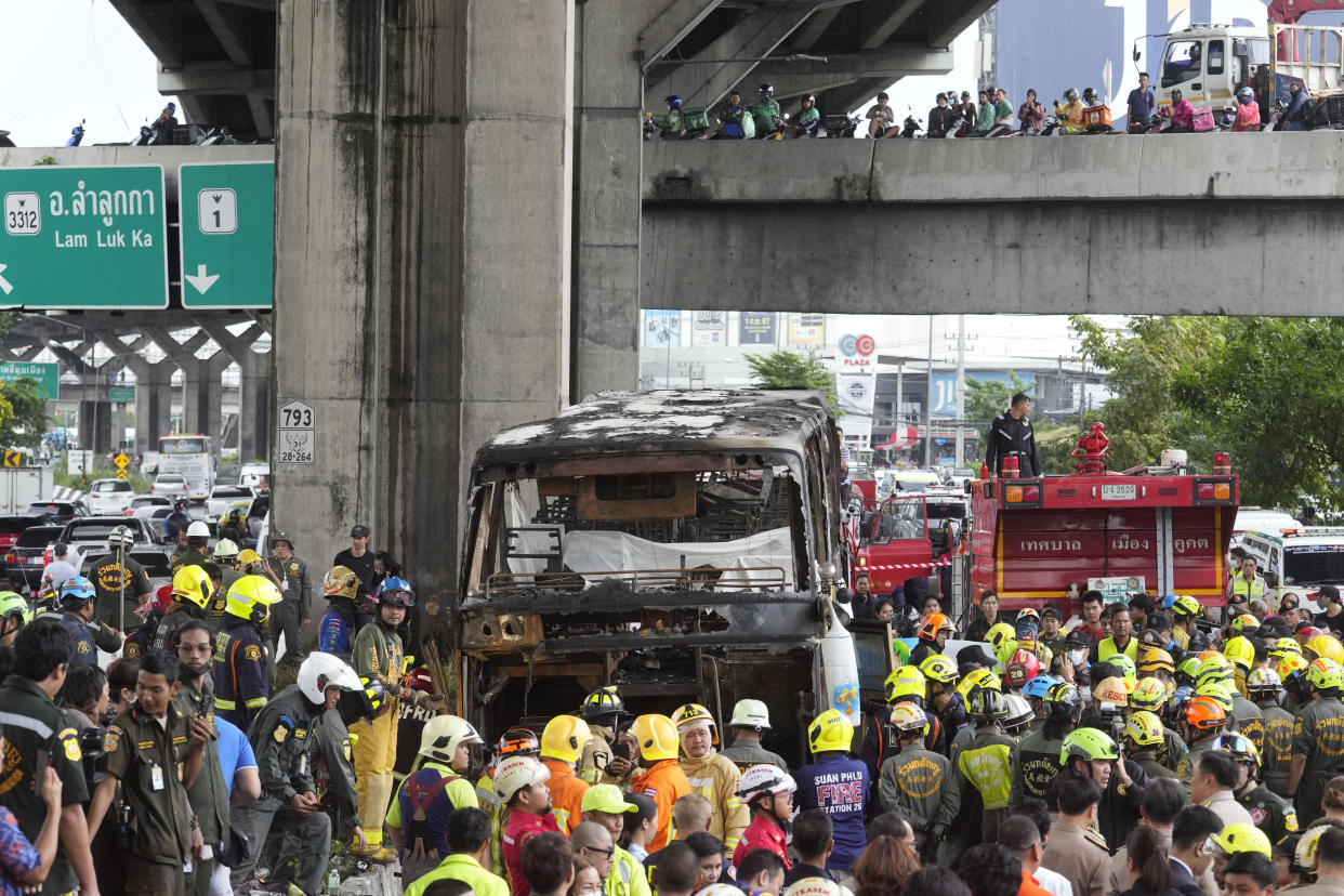 Rescuers gather at the site of a bus that caught fire, carrying young students with their teachers, in suburban Bangkok, Tuesday, Oct. 1, 2024. (AP Photo/Sakchai Lalit)