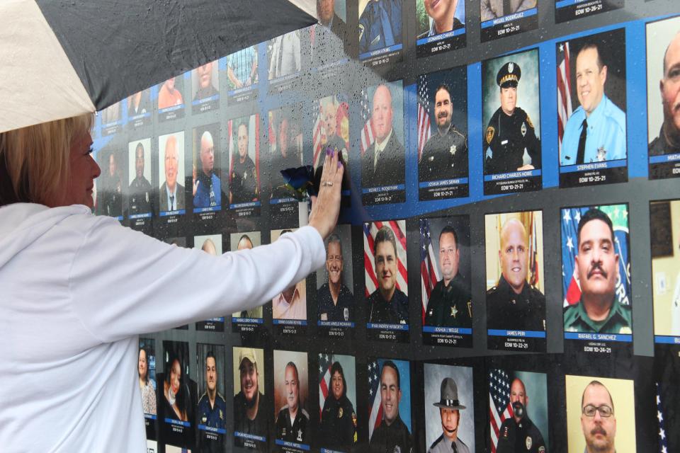 Dawn Powell places a flower next to the photo of her husband, Ty Powell, on a trailer memorializing the 608 law enforcement officers who died in 2021. Ty Powell died from COVID-19 on Oct. 13, 2021. The trailer stopped at the Windsor Police Department on Aug. 15, 2022, as part of the national Ride to Remember.