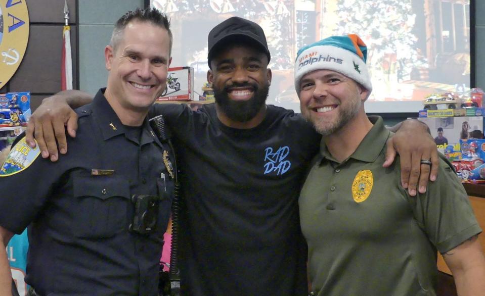 Raheem Mostert is flanked by NSB Deputy Police Chief Eric Feldman (left) and and Captain Chris Kirk during Tuesday's toy giveaway.
