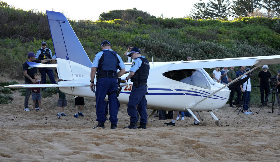 Police stand near a light plane that made an emergency landing on a beach in Sydney Wednesday, May 26, 2021. The recreational plane landed safely on a Sydney beach with three people aboard including a baby on Wednesday after its single engine failed, officials said. (AP Photo/Mark Baker)