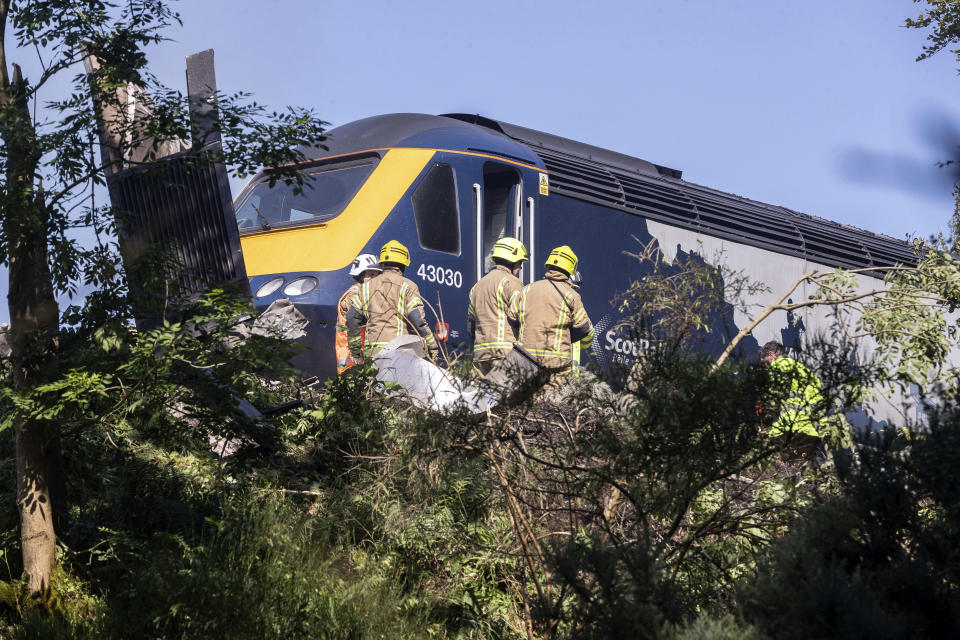 Emergency services attend the scene of a derailed train in Stonehaven, Scotland, Wednesday Aug. 12, 2020. Police and paramedics were responding Wednesday to a train derailment in northeast Scotland, where smoke could be seen rising from the site. Officials said there were reports of serious injuries. The hilly area was hit by storms and flash flooding overnight. (Derek Ironside/Newsline-media via AP)