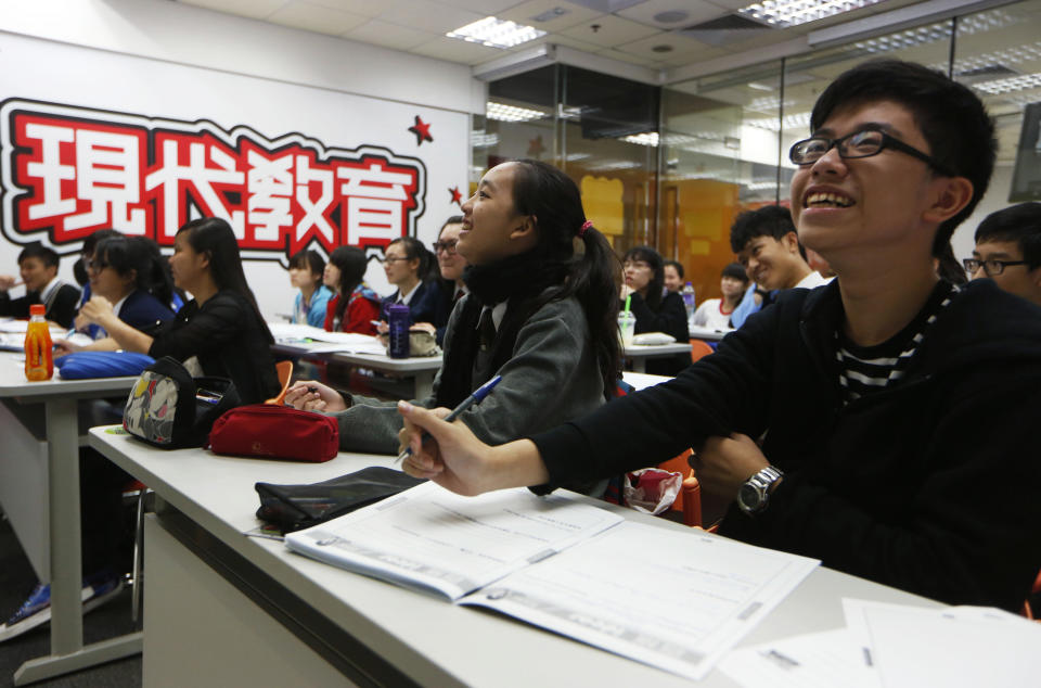 In this Dec. 9, 2013 photo, students laugh during an English grammar lesson by Tony Chow in a classroom of Modern Education in Hong Kong. The 30-year-old teaches English grammar to thousands of secondary school pupils, who attend his after-school lessons or watch video replays of them at Modern Education’s 14 branches. Chow is a celebrity tutor in Hong Kong, where there’s big money to be made offering extracurricular lessons to parents desperately seeking an edge for their children preparing for the city’s intense public entrance exam for university. (AP Photo/Kin Cheung)