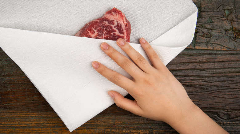 Patting the steak dry with a paper towel