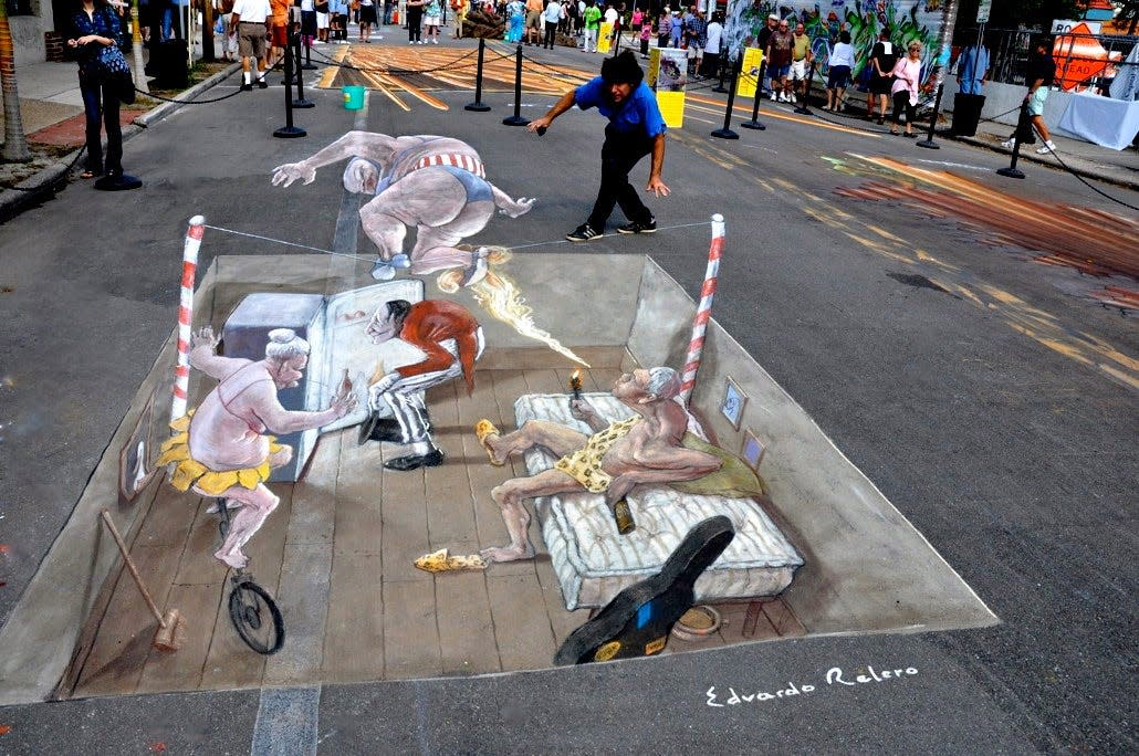 Eduardo Relero, a 3-D pavement artist from Spain walks a tightrope as part of an illusion he created in Sarasota. He is one of about 20 3-D pavement artists scheduled to create work in Sarasota from Oct. 20 to Oct. 31,as the Chalk Festival morphs into a free visual event, after Hurricane Ian forced the cancellation of the planned event at the Venice Municipal Airport.