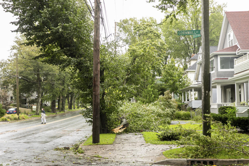A woman crosses the street to avoid downed power lines and trees in Halifax, Nova Scotia, on Saturday, Sept. 16, 2023. Severe conditions were predicted across parts of Massachusetts and Maine, and hurricane conditions could hit the Canadian provinces of New Brunswick and Nova Scotia, where the storm, Lee, downgraded early Saturday from hurricane to post-tropical cyclone, was expected to make landfall later in the day. (Kelly Clark /The Canadian Press via AP)