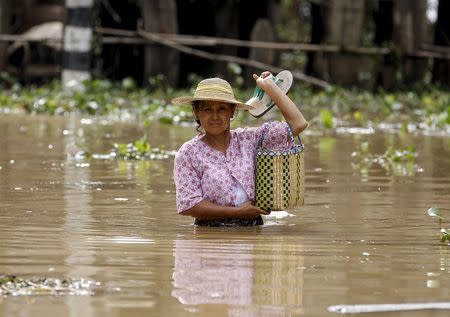 A woman wades through a flooded road in a village at Kawlin township, Sagaing division, Myanmar July 23, 2015. REUTERS/Soe Zeya Tun