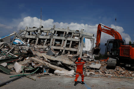 A rescue team member walks in front of the ruins of Roa-Roa Hotel after earthquake hit in Palu, Sulawesi Island, Indonesia, October 2, 2018. REUTERS/Beawiharta