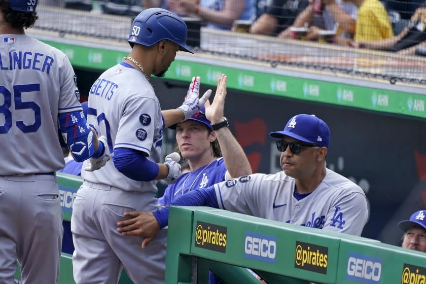 Los Angeles Dodgers' Mookie Betts, center, is greeted at the dugout steps by manager Dave Roberts, right, after hitting a solo home run during the first inning of a baseball game in Pittsburgh, Thursday, June 10, 2021. (AP Photo/Gene J. Puskar)