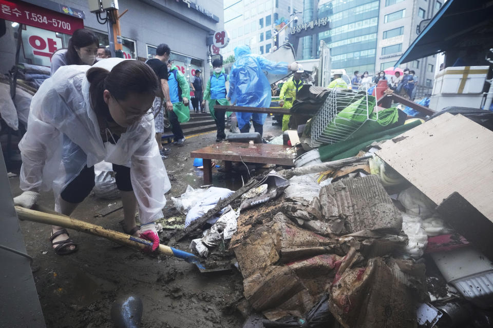 A woman cleans up debris after the water drained from a submerged traditional market following heavy rainfall in Seoul, South Korea, Tuesday, Aug. 9, 2022. Heavy rains drenched South Korea's capital region, turning the streets of Seoul's affluent Gangnam district into a river, leaving submerged vehicles and overwhelming public transport systems. (AP Photo/Ahn Young-joon)