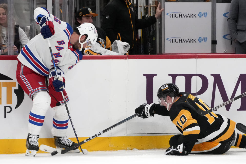 Pittsburgh Penguins' Drew O'Connor (10) reaches for the puck at the feet of New York Rangers' Erik Gustafsson during the second period of an NHL hockey game in Pittsburgh, Wednesday, Nov. 22, 2023. (AP Photo/Gene J. Puskar)