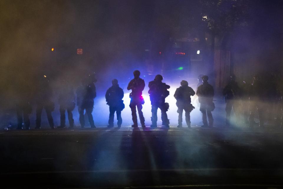 Federal officers walk through tear gas while dispersing a crowd at Mark O. Hatfield U.S. Courthouse in Portland, Ore.