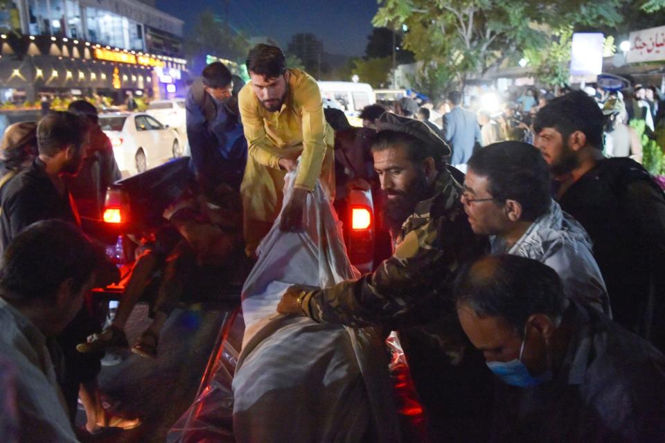 Volunteers and medical staff unload bodies from a pickup truck outside a hospital