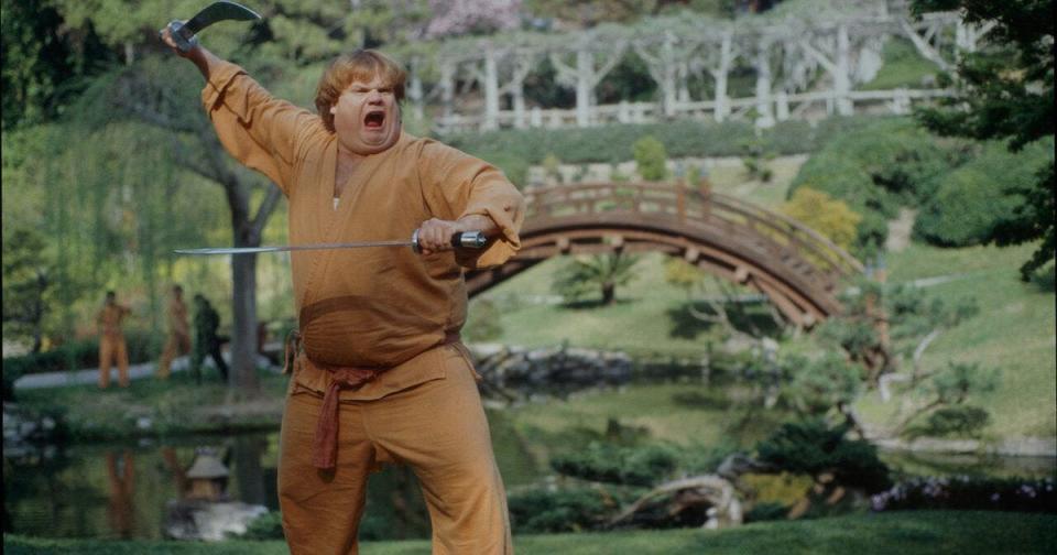 Chris Farley making a face and holding swords