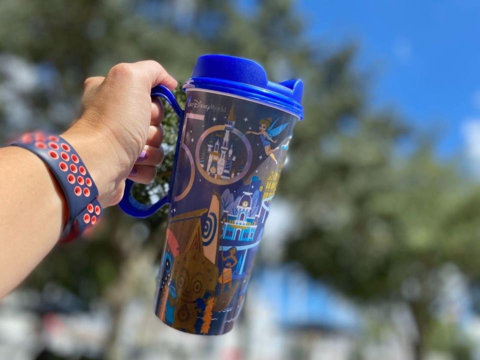 hand holding up a disney 50th anniversary refillable coffee mug