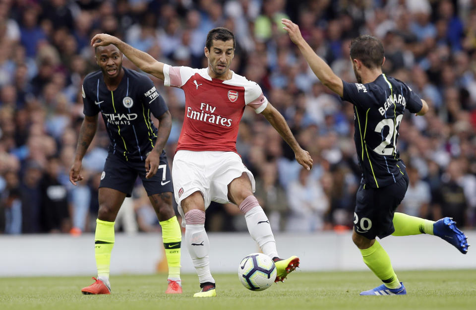 Arsenal's Henrikh Mkhitaryan kicks the ball between Manchester City's Raheem Sterling, left and Manchester City's Bernardo Silva during the English Premier League soccer match between Arsenal and Manchester City at the Emirates stadium in London, England, Sunday, Aug. 12, 2018. (AP Photo/Tim Ireland)