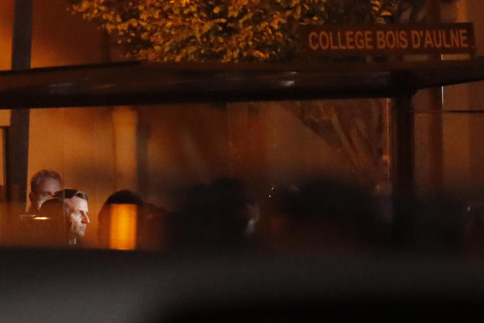 French President Emmanuel Macron, second left, is seen outside a high school after a history teacher who opened a discussion with students on caricatures of Islam's Prophet Muhammad was beheaded, Friday, Oct. 16, 2020 in Conflans-Sainte-Honorine, north of Paris. Police have shot the suspected killer dead. (AP Photo/Michel Euler)