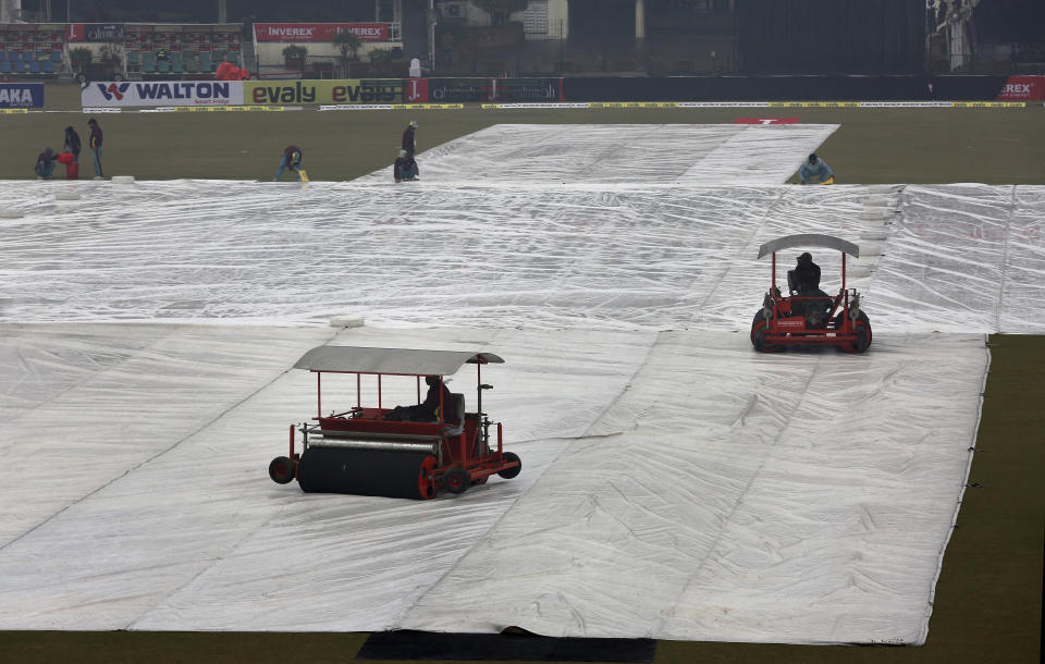 Ground staff work to dry the pitch and field following a light rain at Gaddafi stadium, in Lahore, Pakistan, Monday, Jan. 27, 2020. Pakistan and Bangladesh are scheduled to play the last T20 which is delayed due to rain in Lahore. (AP Photo/K.M. Chaudary)