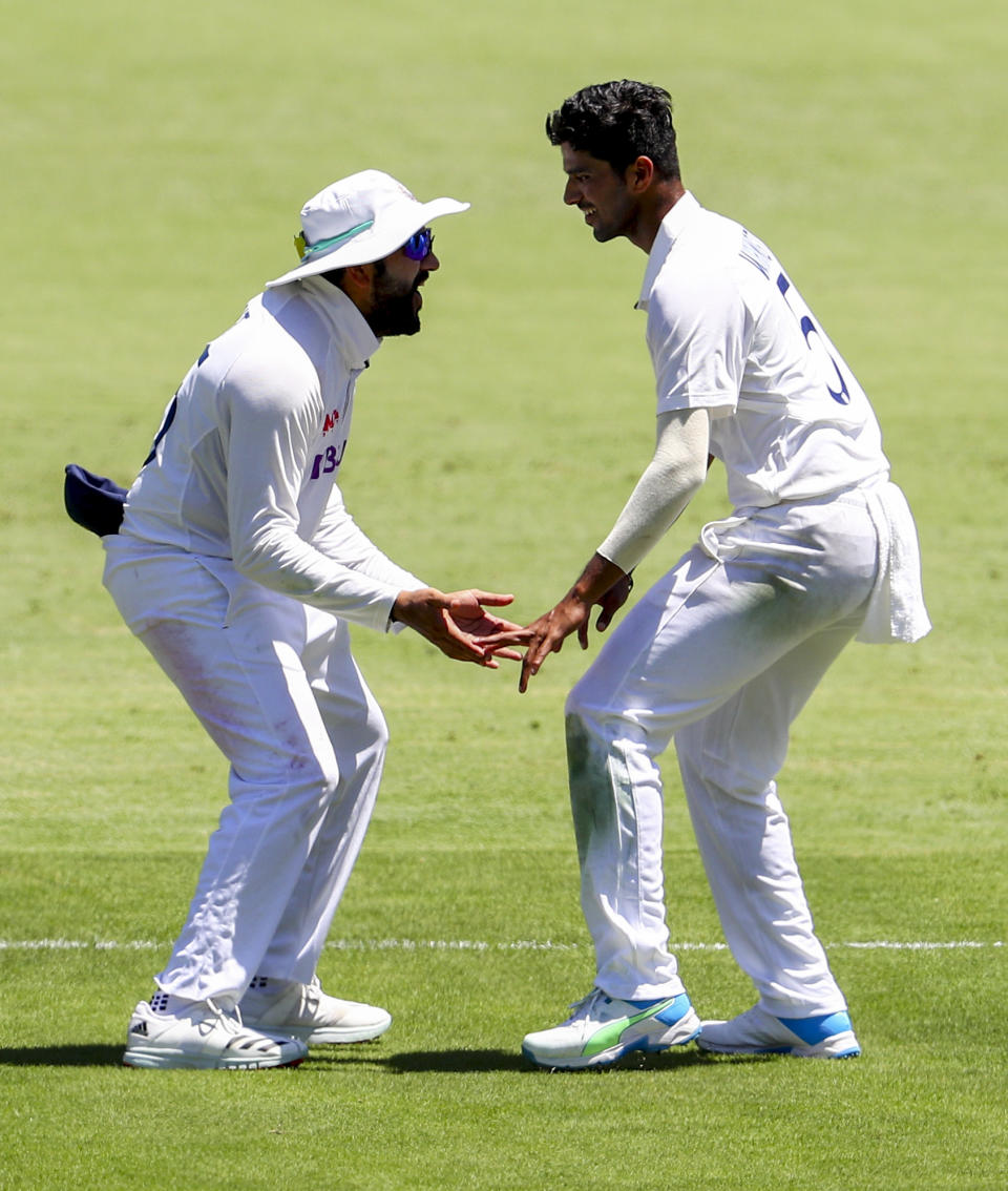 India's Rohit Sharma, left, and teammate Washington Sundar celebrate the dismissal of Australia's Steve Smith during play on the first day of the fourth cricket test between India and Australia at the Gabba, Brisbane, Australia, Friday, Jan. 15, 2021. (AP Photo/Tertius Pickard)