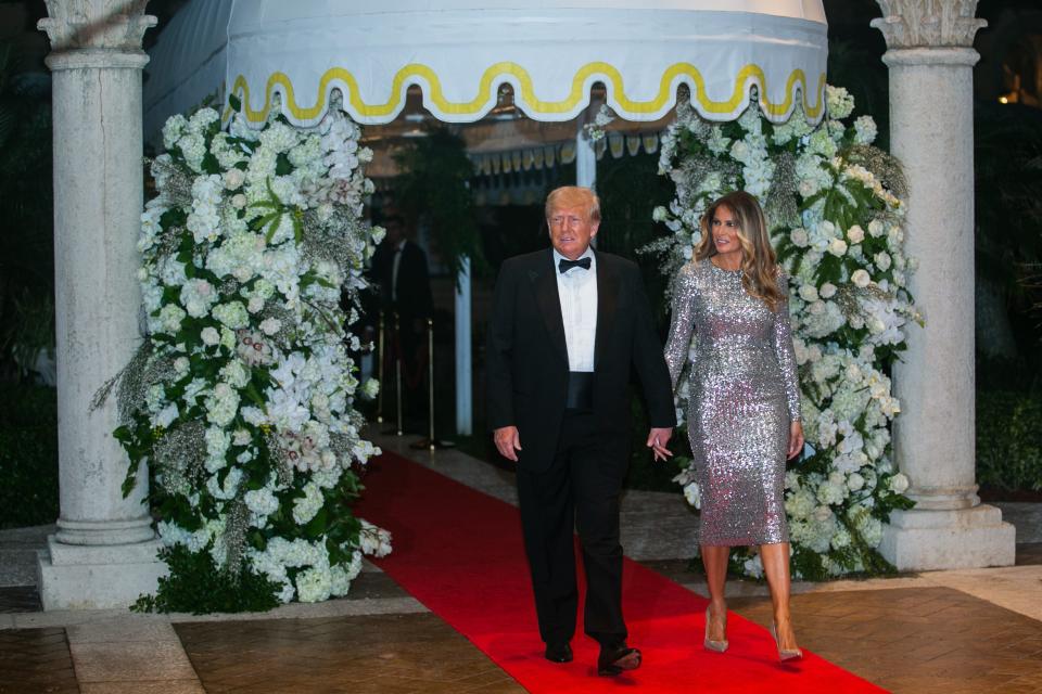 Former President Donald Trump and his wife, Melania, approach the Mar-A-Lago ballroom on the red carpet on New Year's Eve