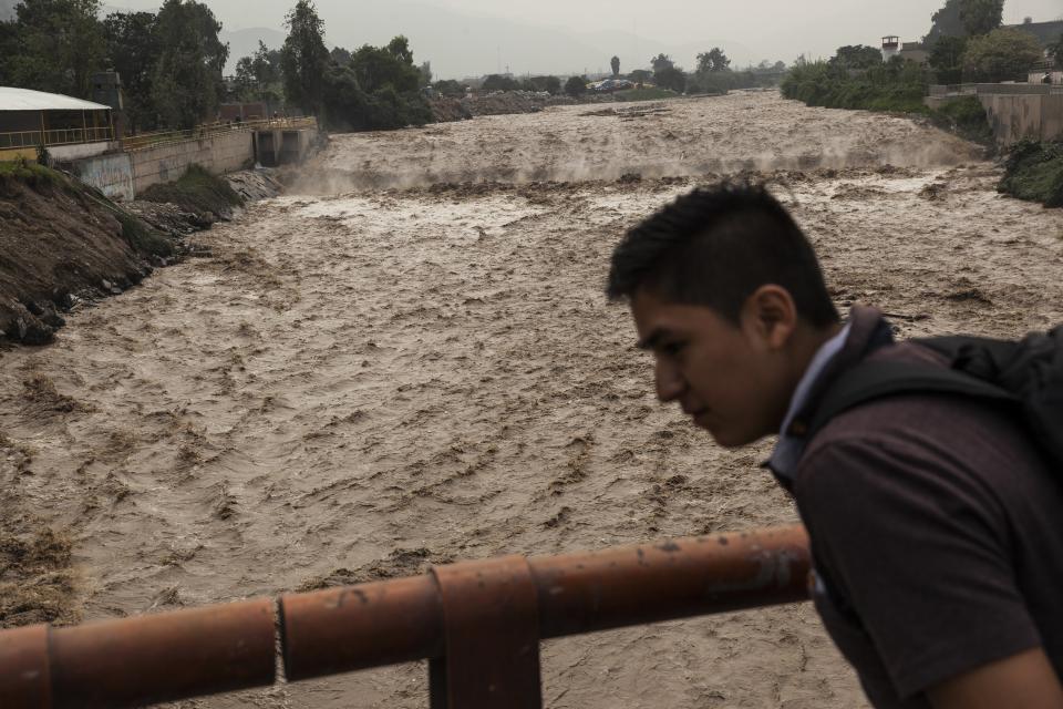 A man looks at the flow of the Huaycoloro river in Lima, Peru, Thursday, March 16, 2017. A new round of unusually heavy rains has killed at least a dozen people in Peru and now threatens flooding in the capital. Authorities said Thursday they expect the intense rains caused by the warming of surface waters in the eastern Pacific Ocean to continue another two weeks. (AP Photo/Rodrigo Abd)